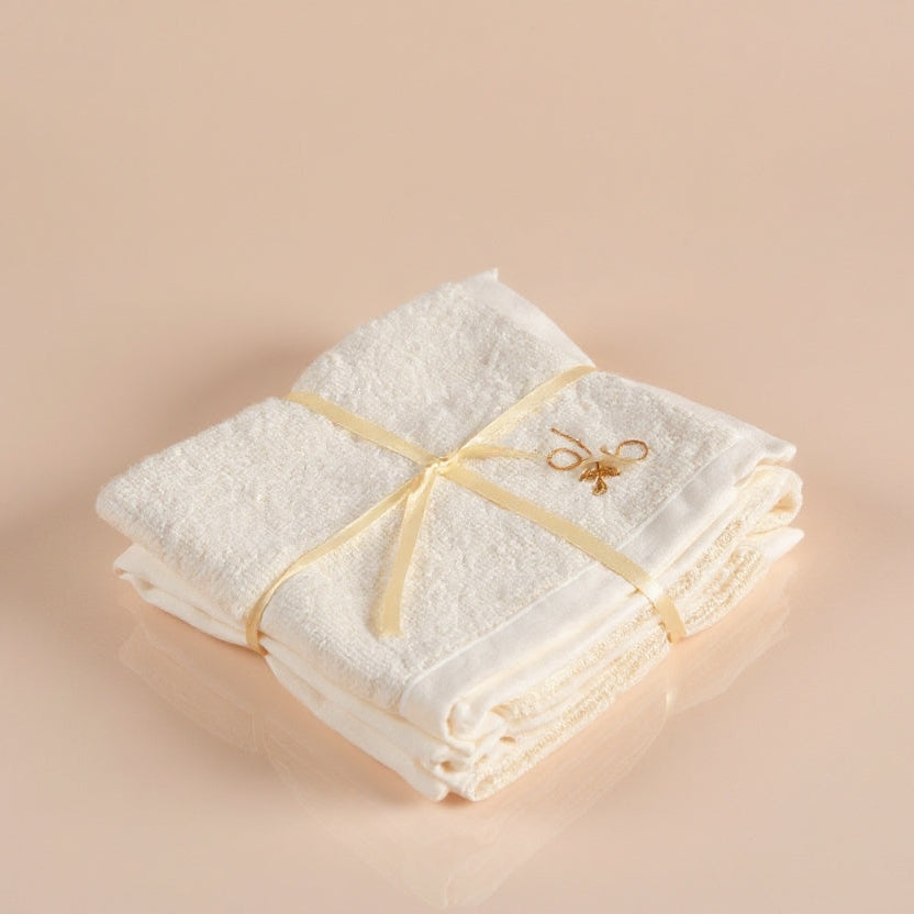 Folded white towel with a gold ribbon on a beige background