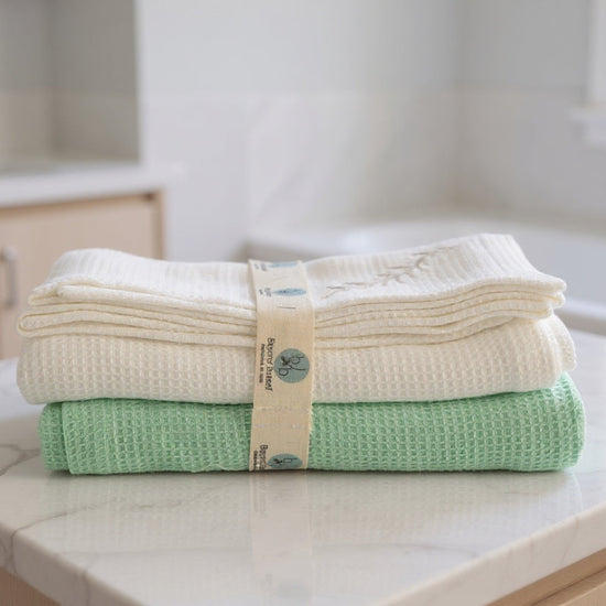 Stack of folded towels on a kitchen counter with a brand label.