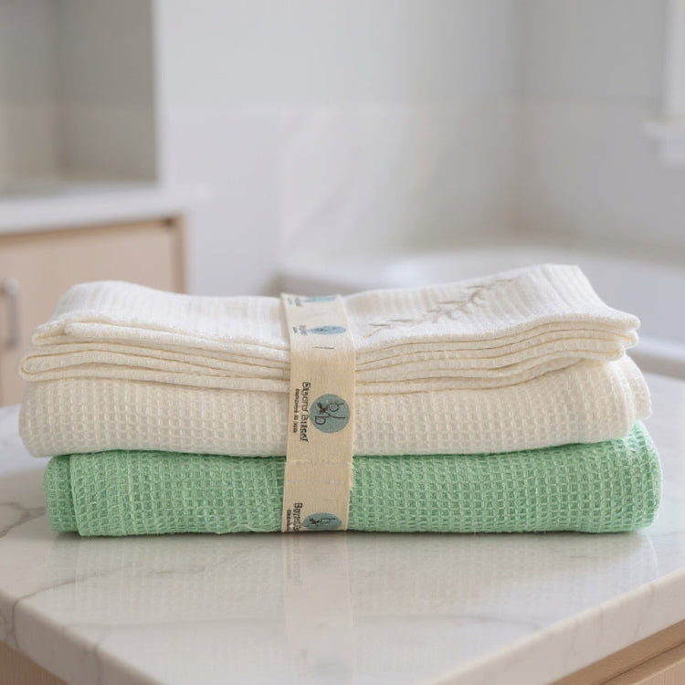 Stack of folded towels on a kitchen counter with a brand label.