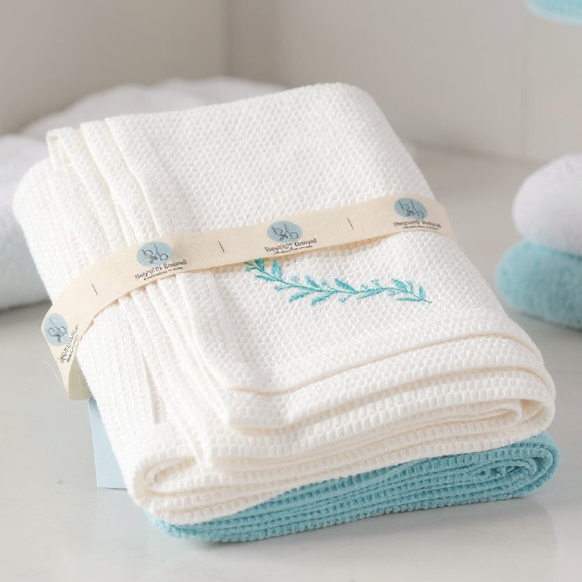 Folded white towel with blue accents and a brand logo on a light surface.