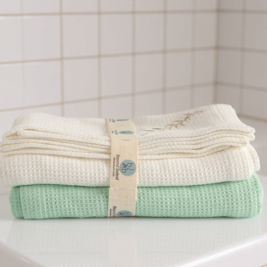Stack of folded towels with a label on a tiled bathroom shelf